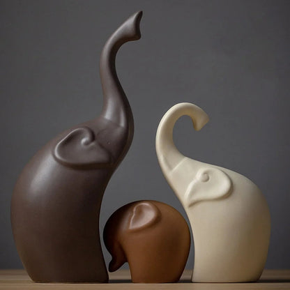 Three ceramic elephant statues in brown and cream colors.