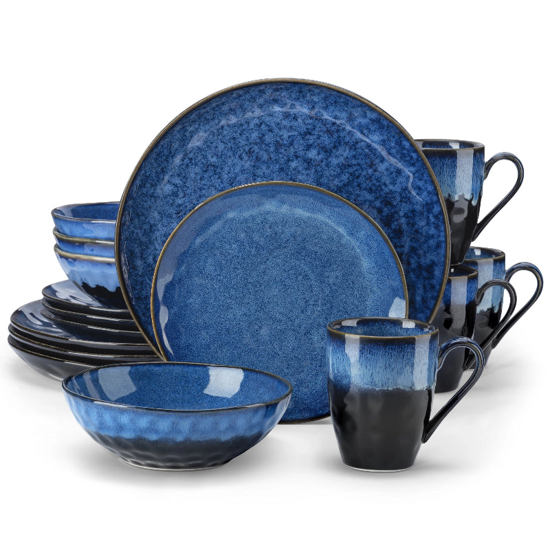 A complete dinnerware set of black and blue ceramic plates, bowls, and mugs is arranged against a white background.
