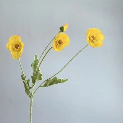 Three yellow poppy flowers with green stems and one poppy bud are arranged in a sparse bouquet against a plain light grey background.
