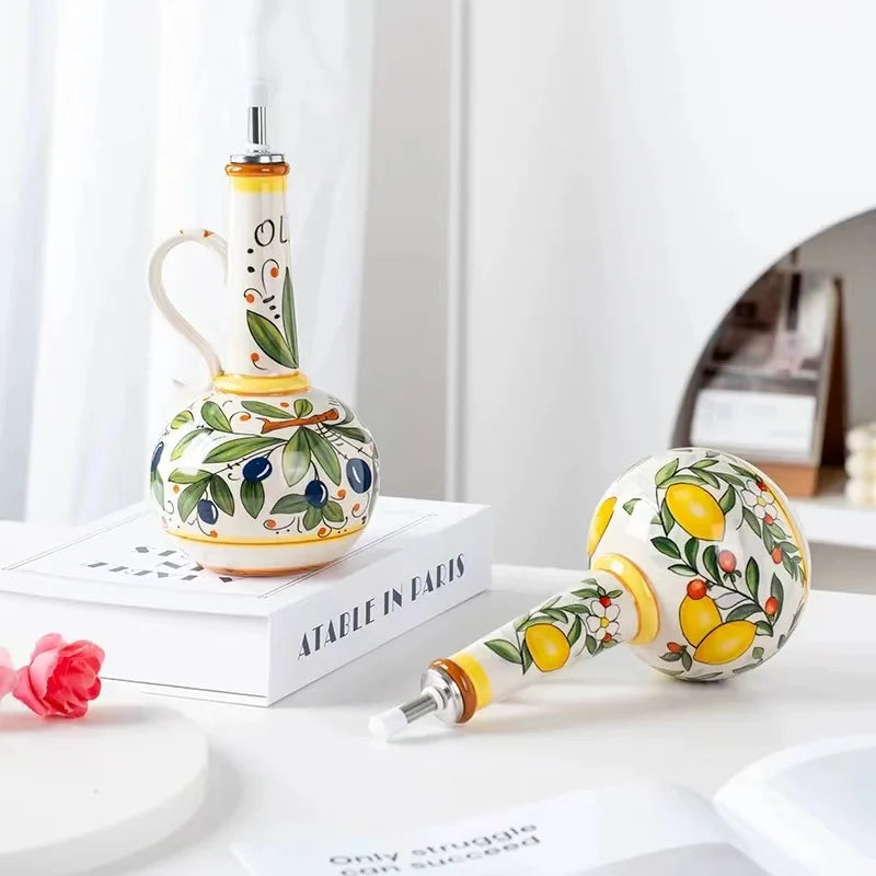 Decorative ceramic oil and vinegar bottles with lemon and olive design on a white surface.