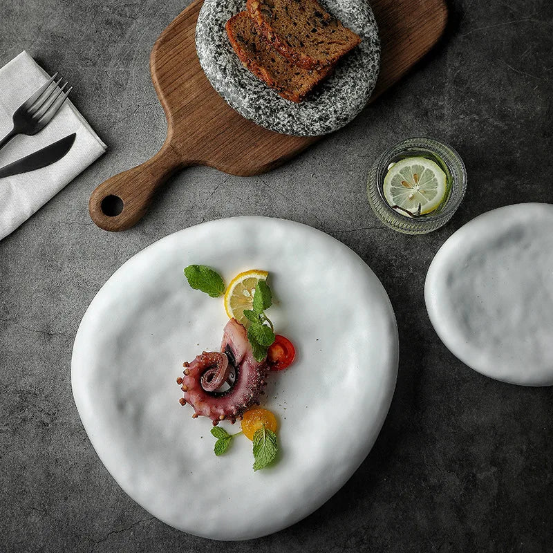 Plated dish with octopus and vegetables on a textured surface