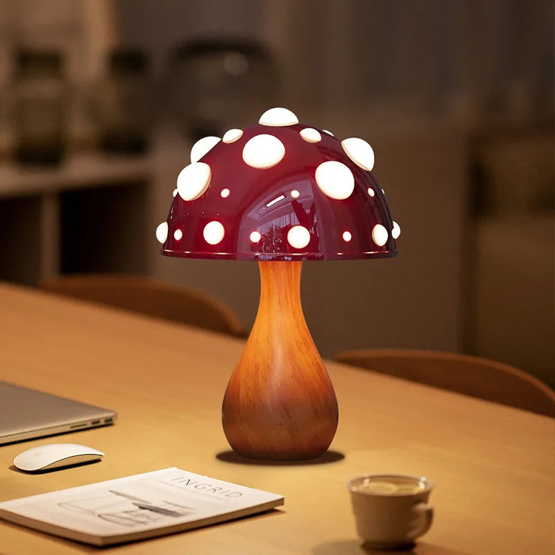 A mushroom-shaped lamp with a red cap and white spots, on a wooden table.