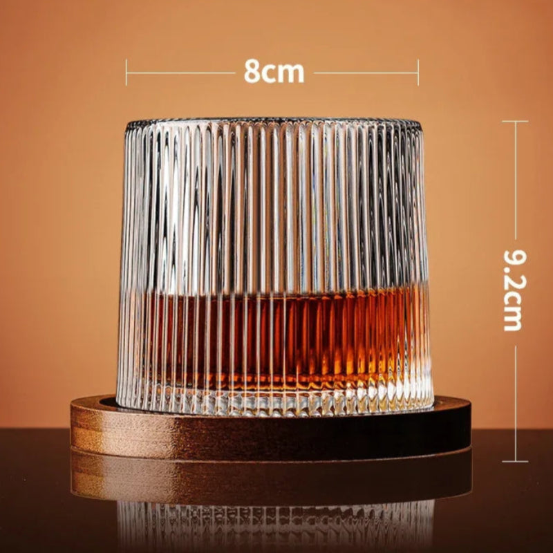 A ribbed glass with amber liquid rests on a wooden coaster, with its dimensions noted.