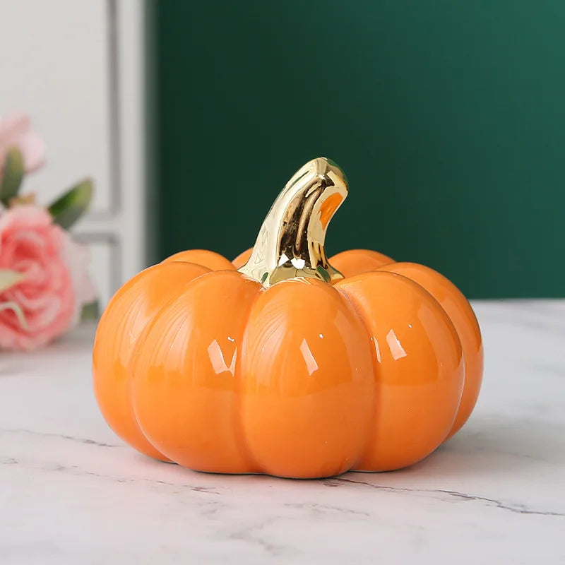 A single glossy orange ceramic pumpkin with a golden stem sits on a marble surface.