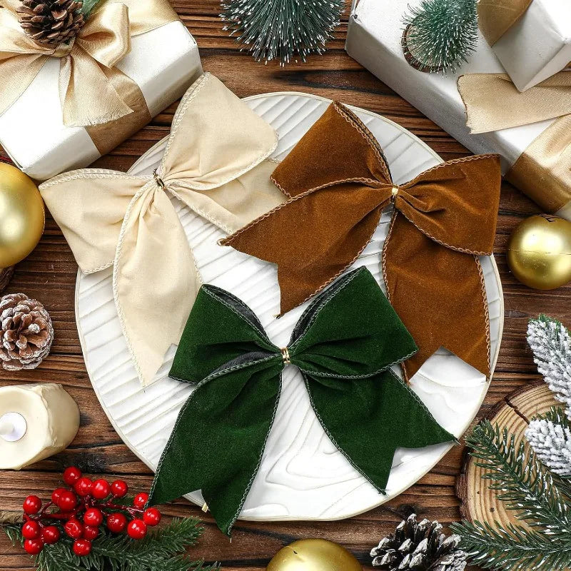 Three velvet Christmas bows (cream, brown, and green) on a white plate, surrounded by holiday decorations and gifts.