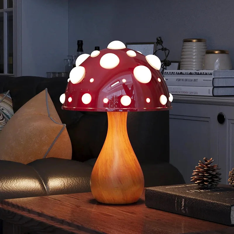 A mushroom-shaped lamp with a red spotted cap and a wooden stem, illuminating a dark room with a book and pinecone on a table.