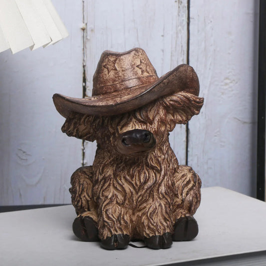Decorative figurine of a cow wearing a cowboy hat on a plain background