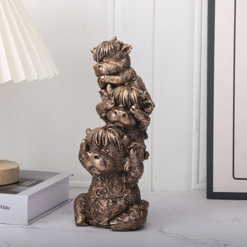 Bronze sculpture of four stacked animals on a white surface with a neutral background
