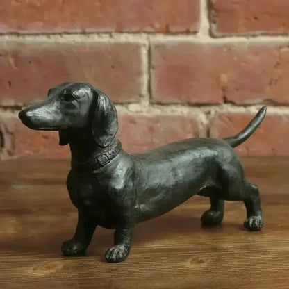 Black dachshund figurine on a wooden surface.