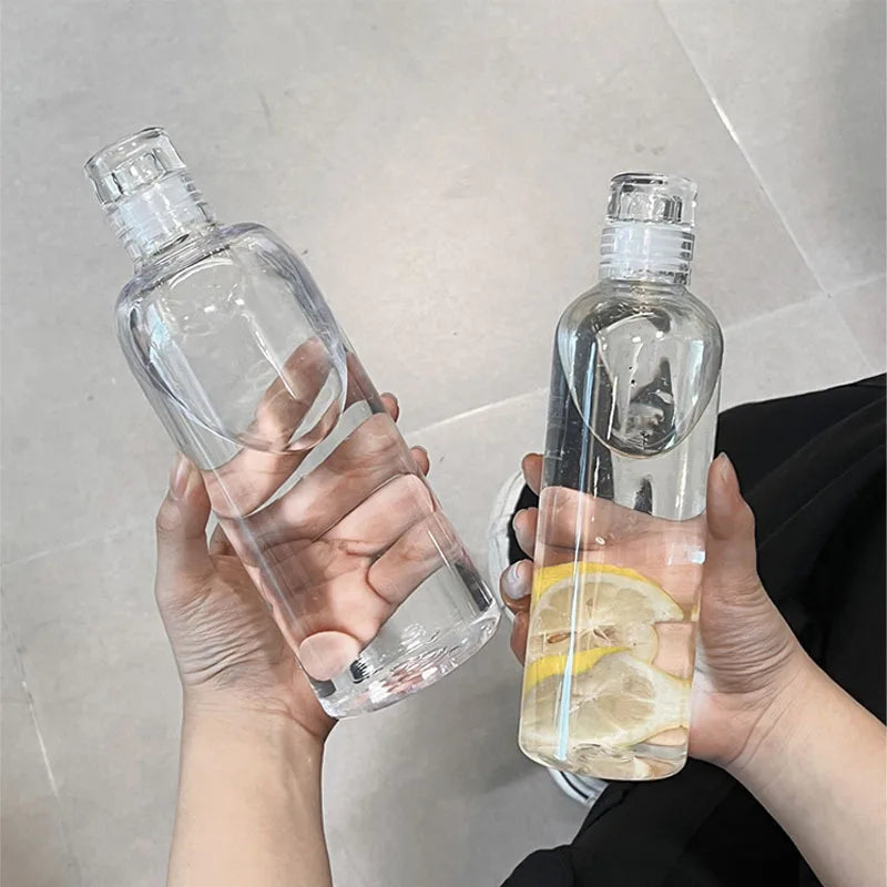 Two hands holding glass water bottles, one with lemon slices.