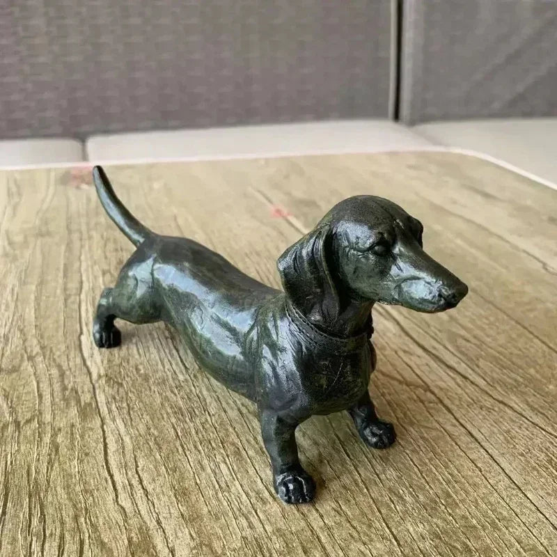 Black dachshund figurine on a textured wooden surface.
