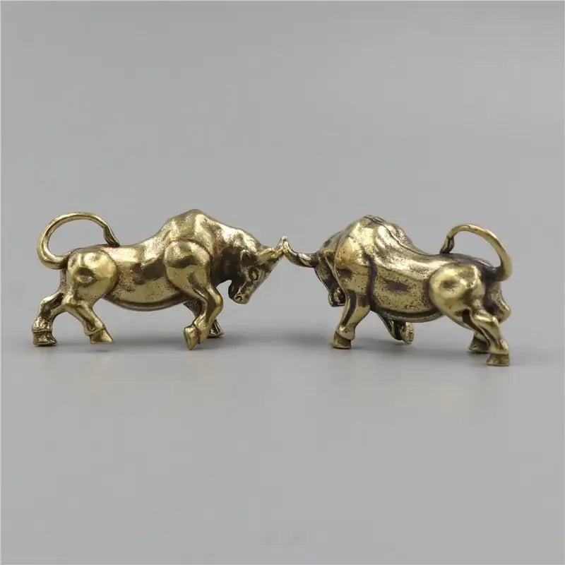 Two brass bull figurines facing each other on a gray background