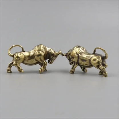 Two brass bull figurines facing each other on a gray background