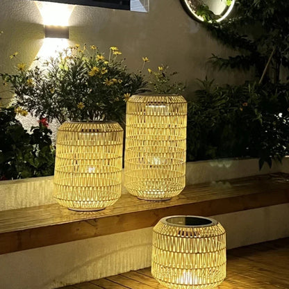 Three woven lanterns on a wooden surface with plants and a wall light in the background