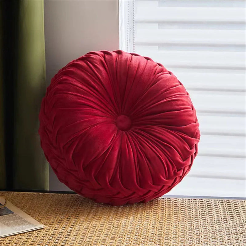 Red round pillow on a textured surface with a window in the background