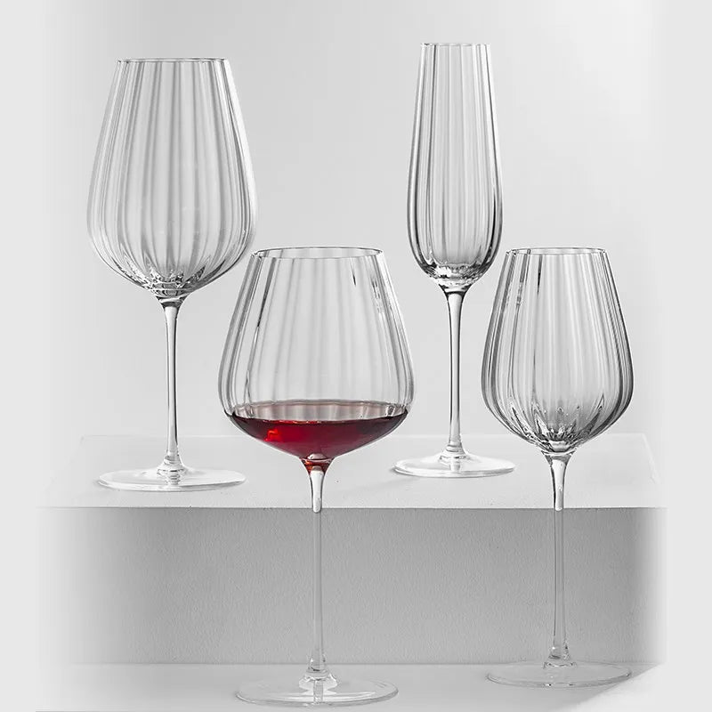 Four fluted glasses, one with red wine.