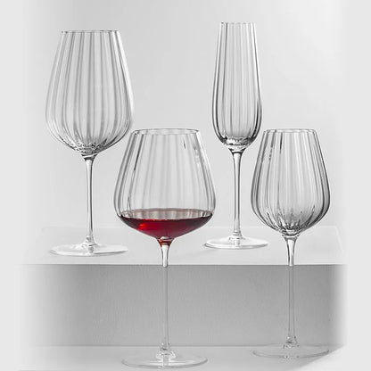 Four fluted glasses, one with red wine.