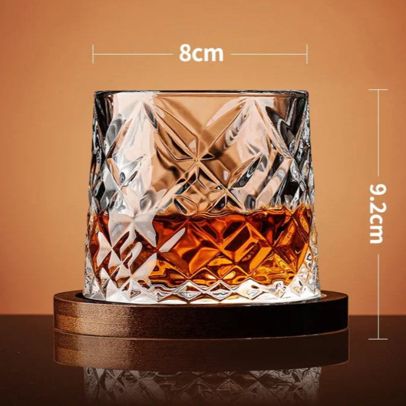 A faceted, diamond-patterned whiskey glass with amber liquid rests on a wooden coaster, with its dimensions noted.