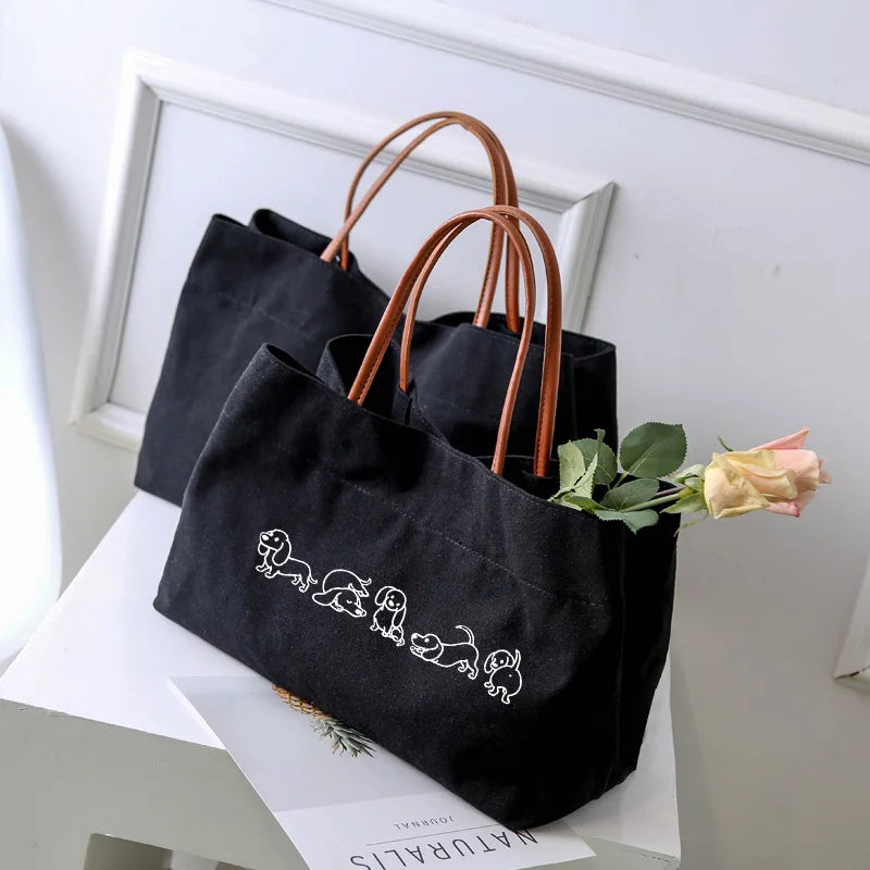 Two black canvas tote bags, one with cute white dog outlines.