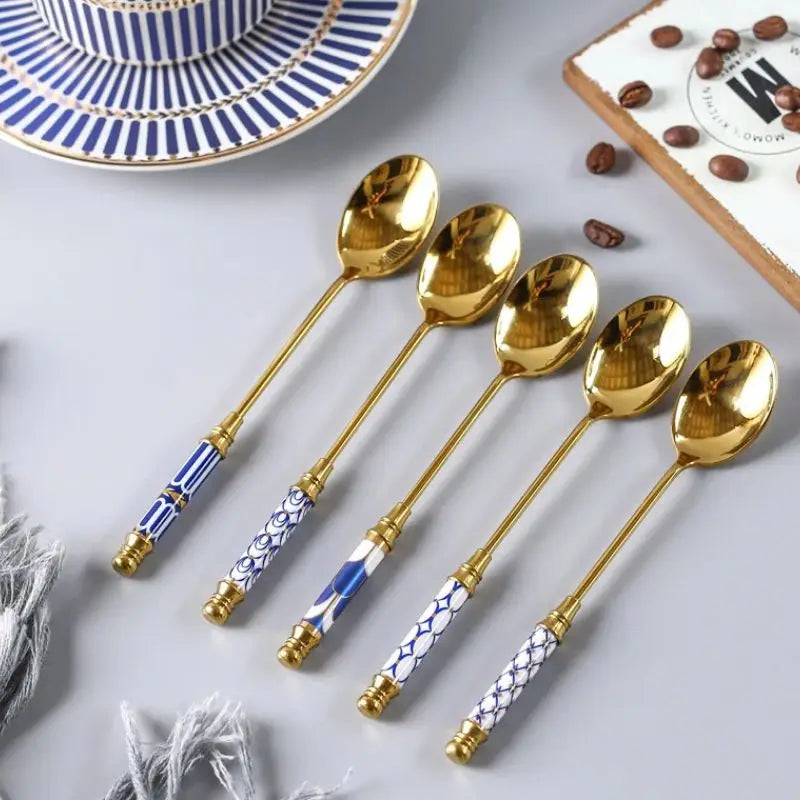Set of gold spoons with decorative handles on a light gray surface.