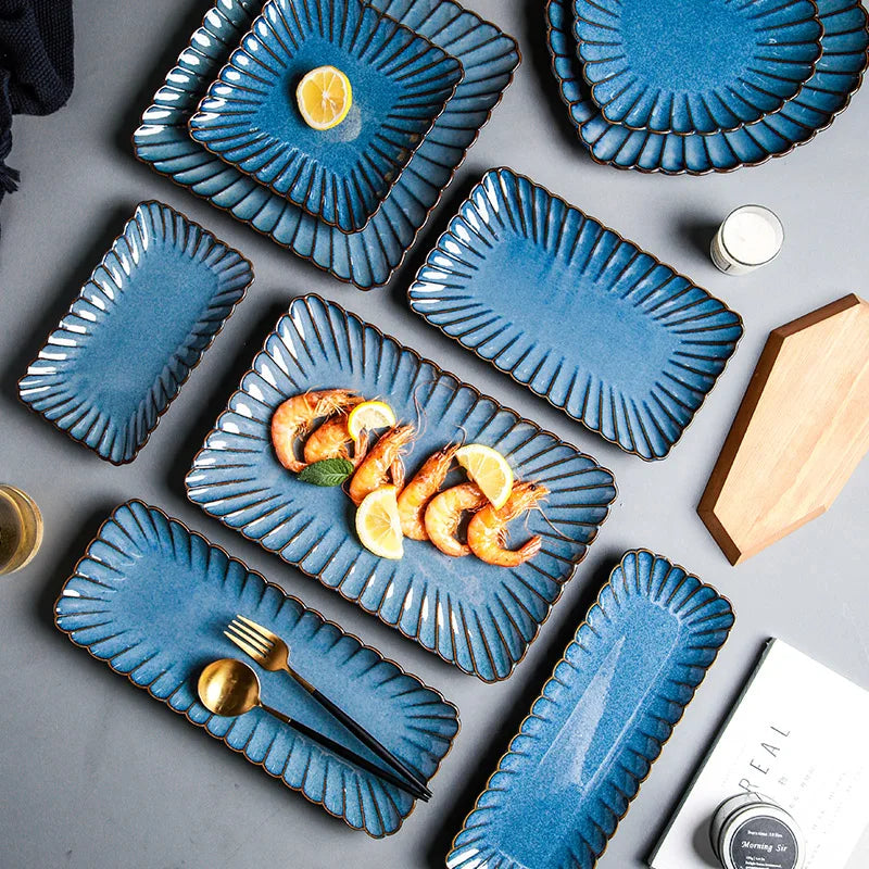 An overhead shot of rectangular blue ceramic plates, some with shrimp and lemon.