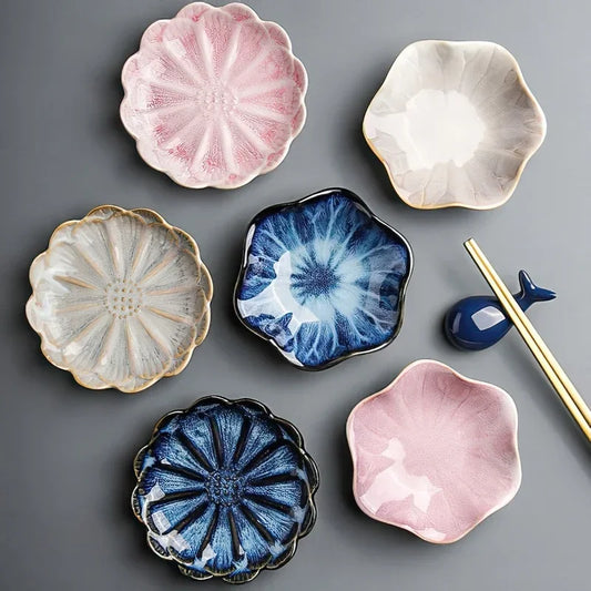 A group of small, flower-shaped condiment or sauce dishes in various colors, with a pair of chopsticks and a whale-shaped chopstick rest.