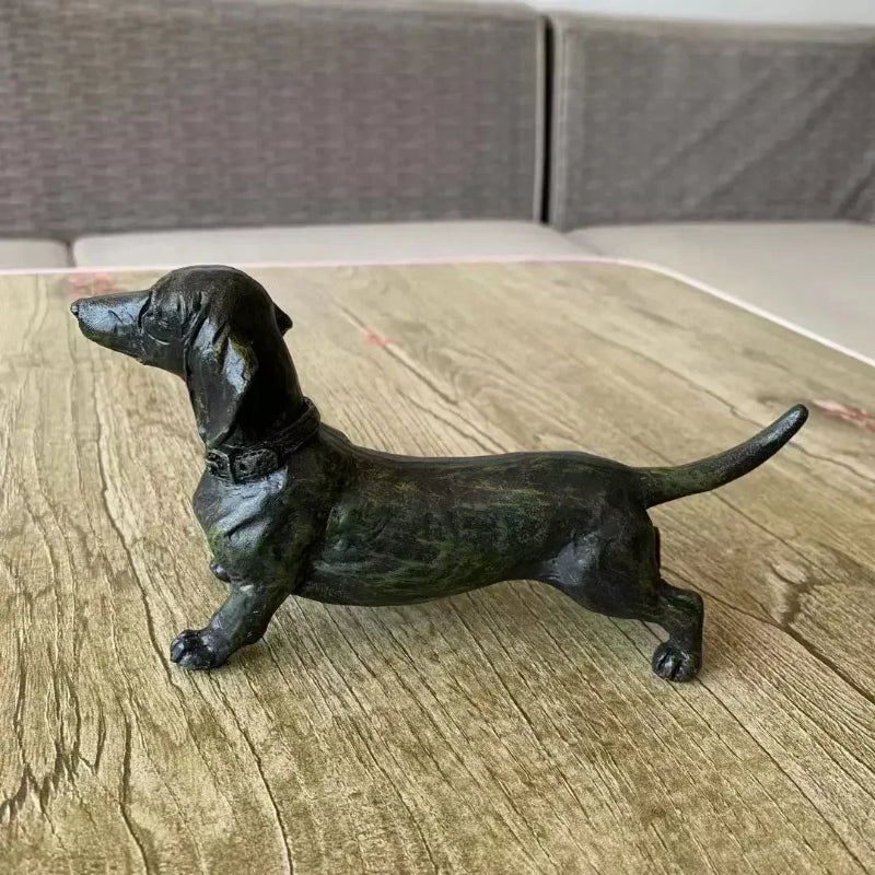 Black dachshund figurine on a textured wooden surface.