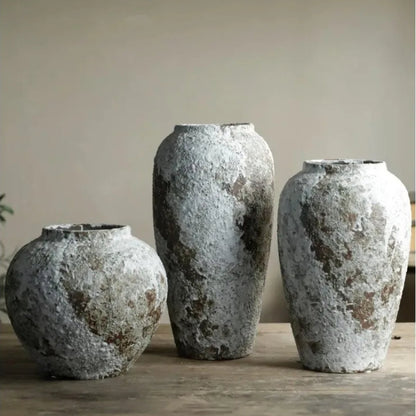 Three textured ceramic vases on a wooden surface with a neutral background