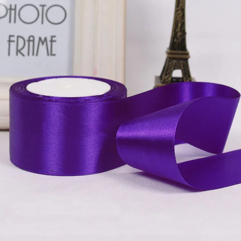 Purple satin ribbon with a spool on a white background