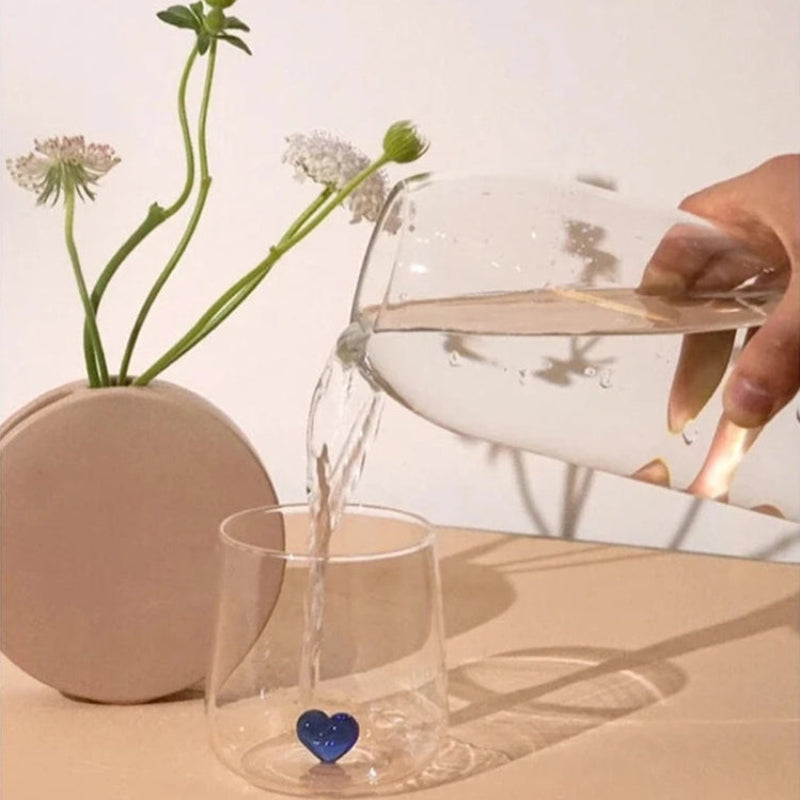 Water pouring into a glass with a blue heart.