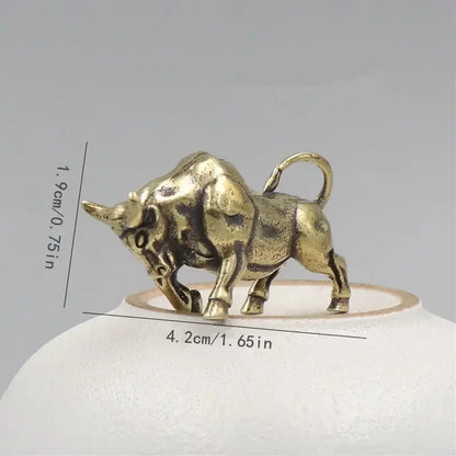 Bronze bull figurine with measurements on a gray background