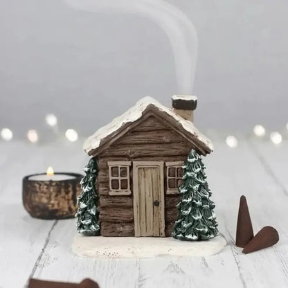 Small wooden cabin ornament with snow and trees on a white background