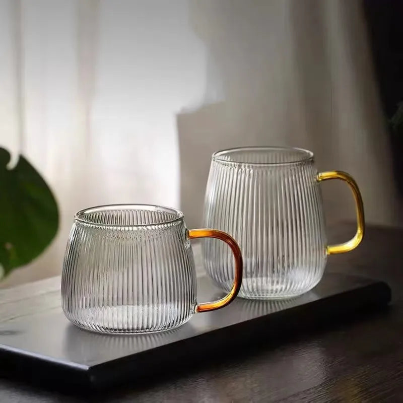 Two empty, ribbed glass mugs with gold-colored handles.