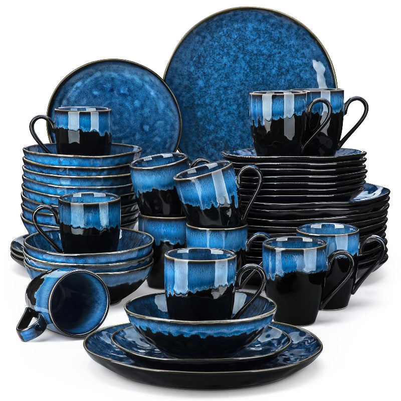 A large dinnerware set of black and blue ceramic plates, bowls, and mugs is arranged in stacks against a white background.