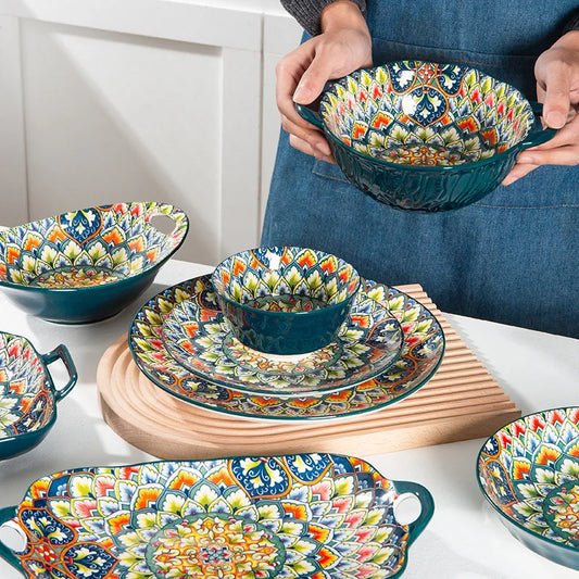 A person holding a large, ornate bowl from a matching set of dinnerware.