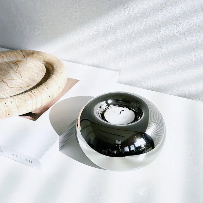 Silver bowl on a white surface with a marble object in the background