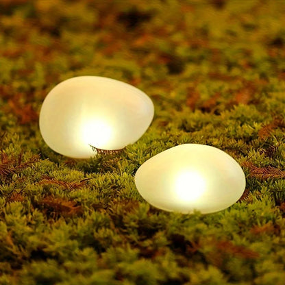 Two white, glowing, egg-shaped lights rest on a bed of moss and dried pine needles.