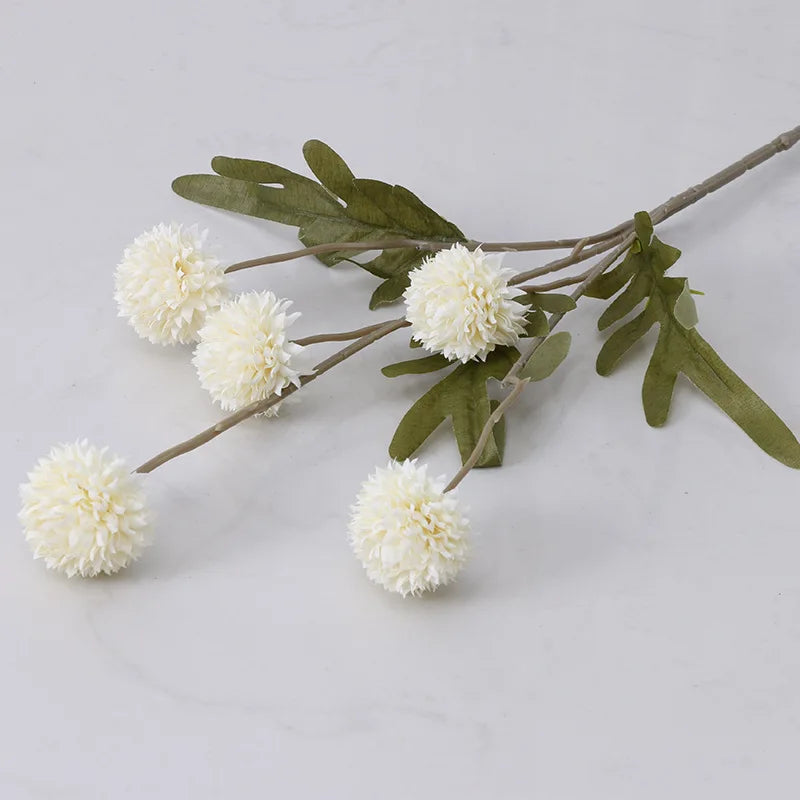A single stem of artificial white dahlia flowers with green leaves.