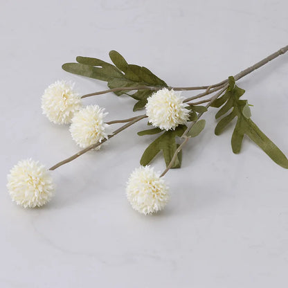 A single stem of artificial white dahlia flowers with green leaves.