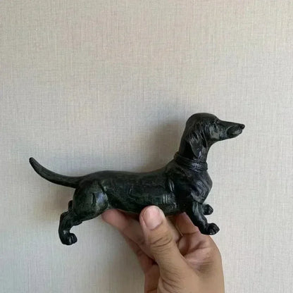 Hand holding a black dachshund figurine.