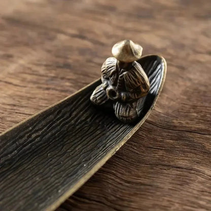 Bronze figurine of a person on a leaf against a wooden background
