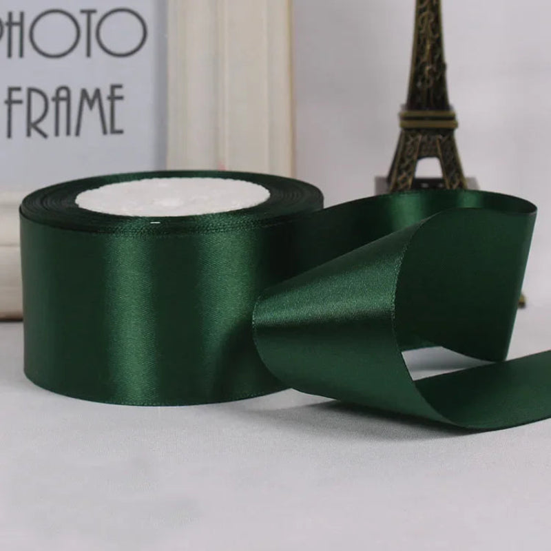 Green satin ribbon with a small section unrolled on a neutral background