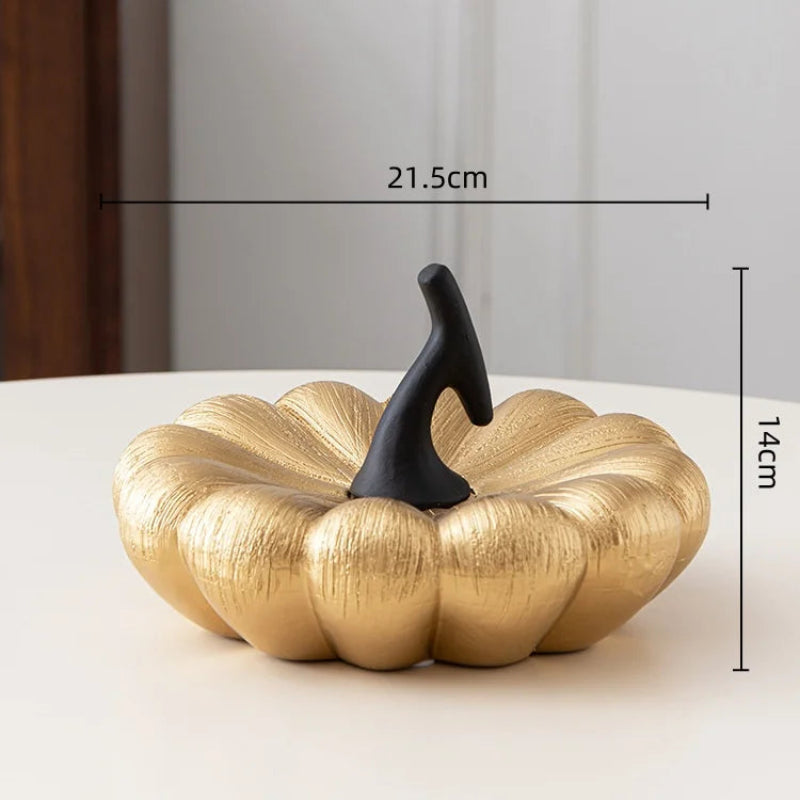A shiny, golden decorative pumpkin with a black stem. It measures 21.5cm wide and 14cm high.