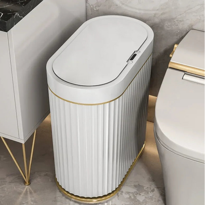 Tall, oval, white, smart trash can with vertical fluting and gold base and trim.