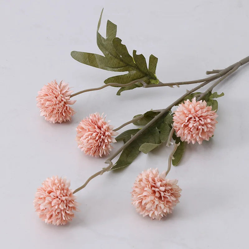 A single stem of artificial pink dahlia flowers with green leaves.