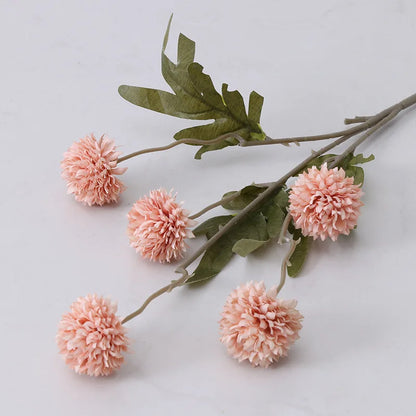 A single stem of artificial pink dahlia flowers with green leaves.