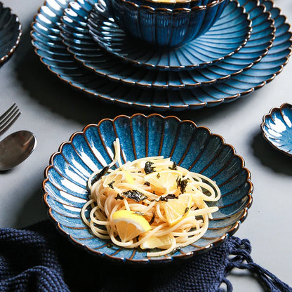A bowl of pasta with lemon and seaweed, set on a blue ceramic dish.