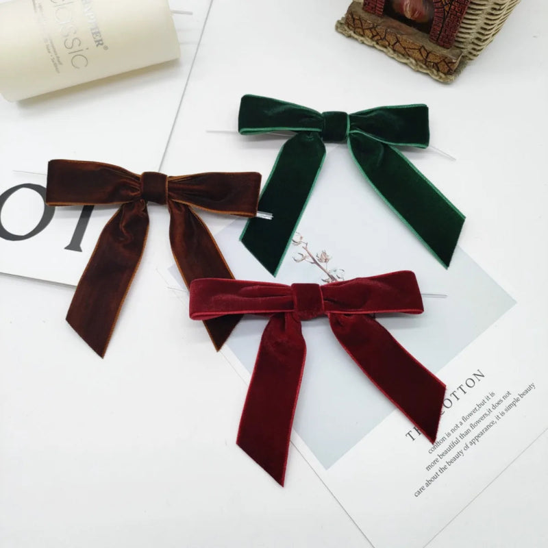 Three velvet bows in brown, green, and red on a magazine page.