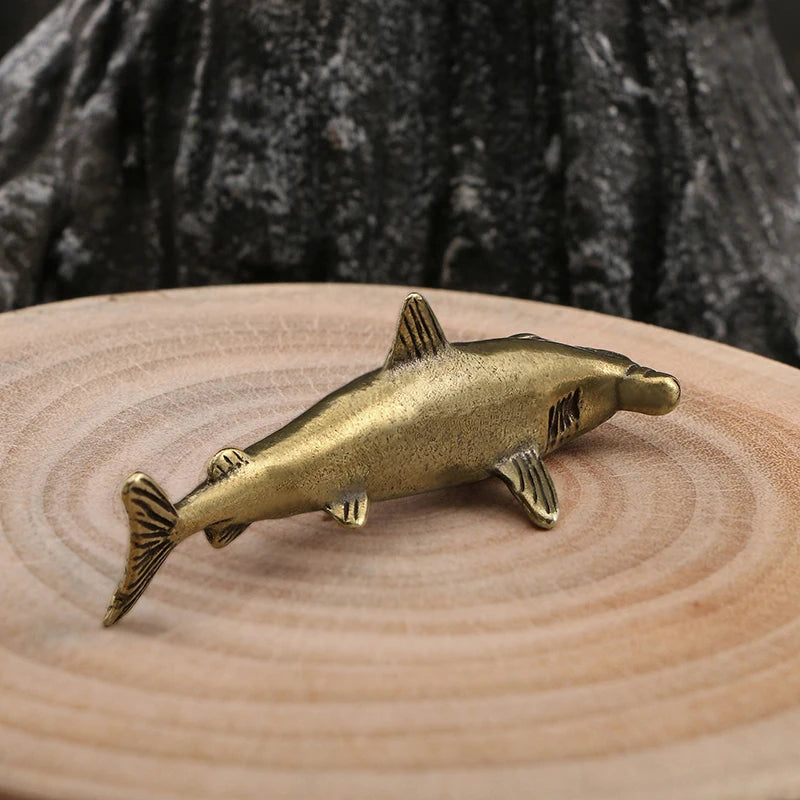 Bronze fish figurine on a wooden surface with a dark textured background