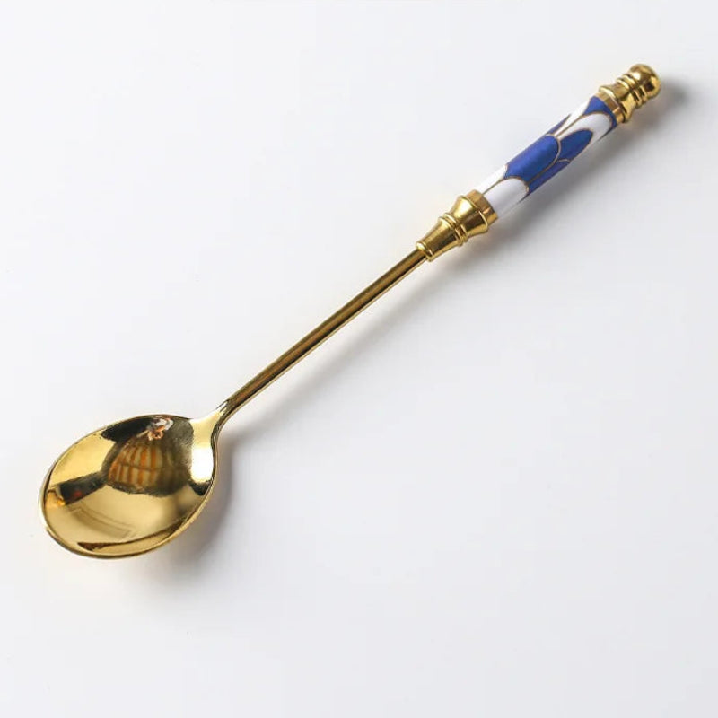 Gold spoon with blue and white handle on a white background